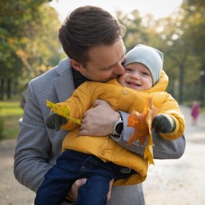 Tėtis glėbyje laiko besijuokiantį vienerių metų sūnų