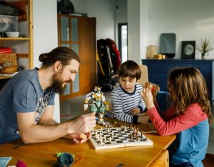 Tėtis su sūnumis žaidžia šachmatais