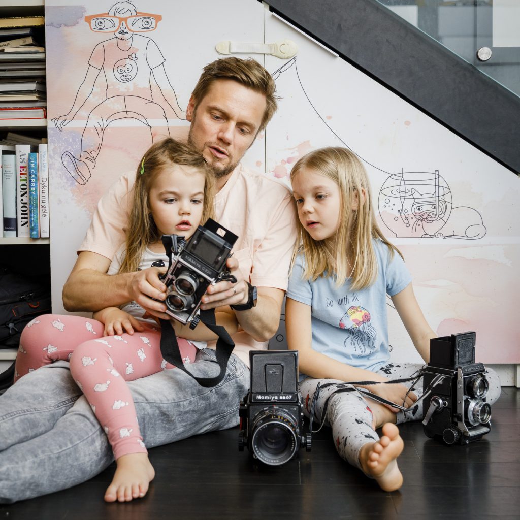 Tėtis dviem mažom dukrom rodo foto kamerą