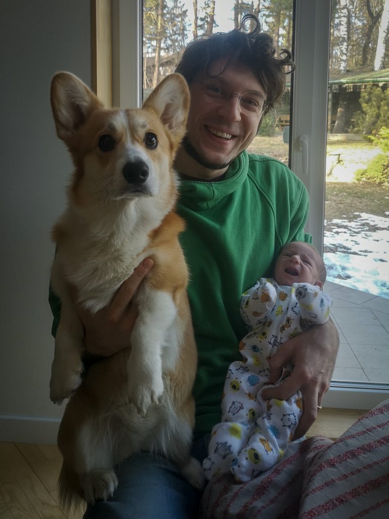 Tėtis ant kelių laiko kūdikį ir korgio veislės šuniuką