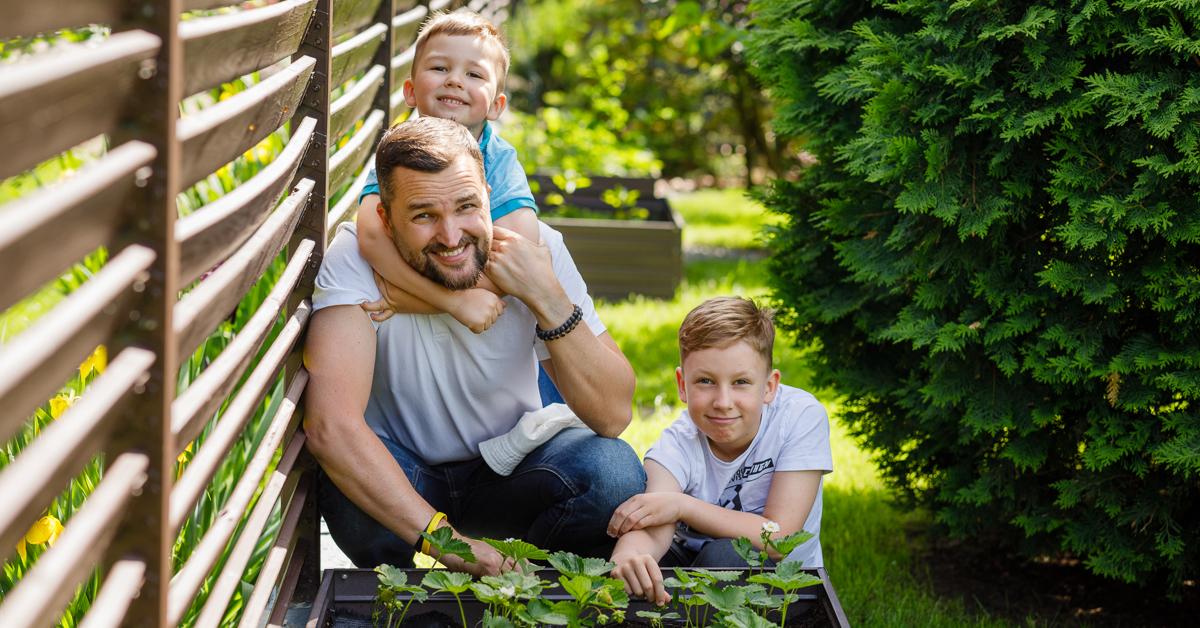 T4tis su dviem sūnumis linksmai žiūri į kamerą sode
